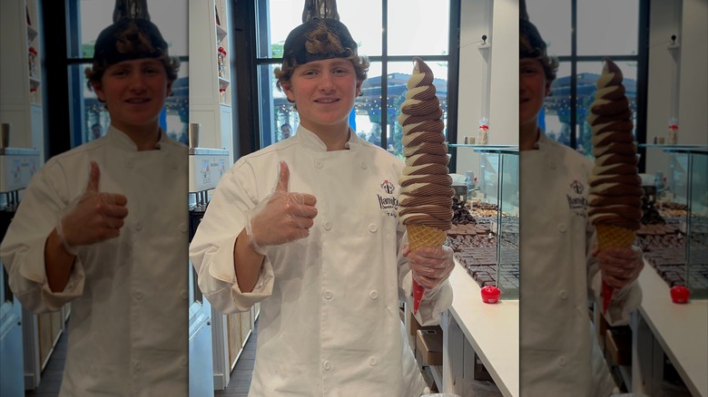 young owner holding a giant cone and giving a thumbs up