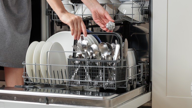 Person placing aluminum foil into a dishwasher