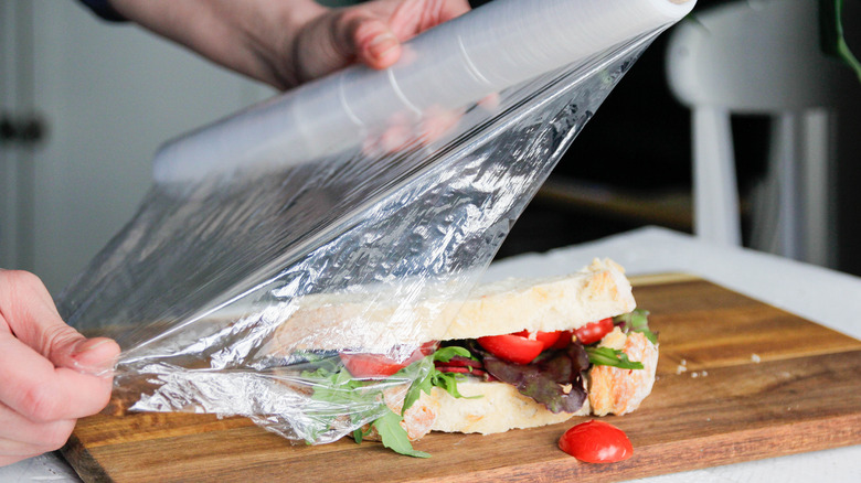 Someone wrapping a sandwich in plastic wrap