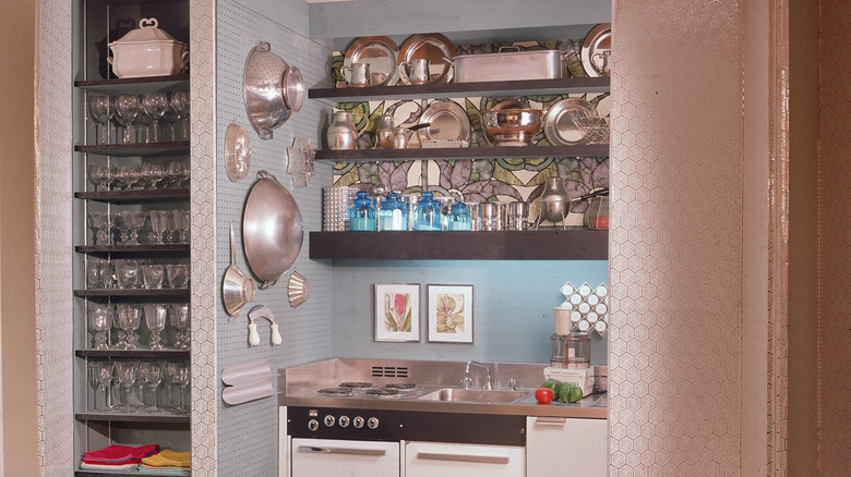 A charming vintage kitchen with wall shelves lined with kitchenware and a counter equipped with a stove top and sink