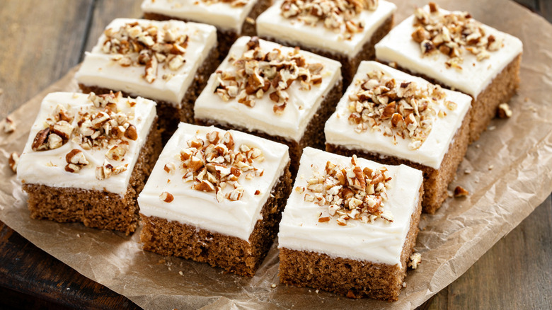 Spice cake with cream cheese frosting has been sliced into squares.
