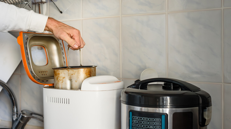 A person's hand is seen using a bread maker