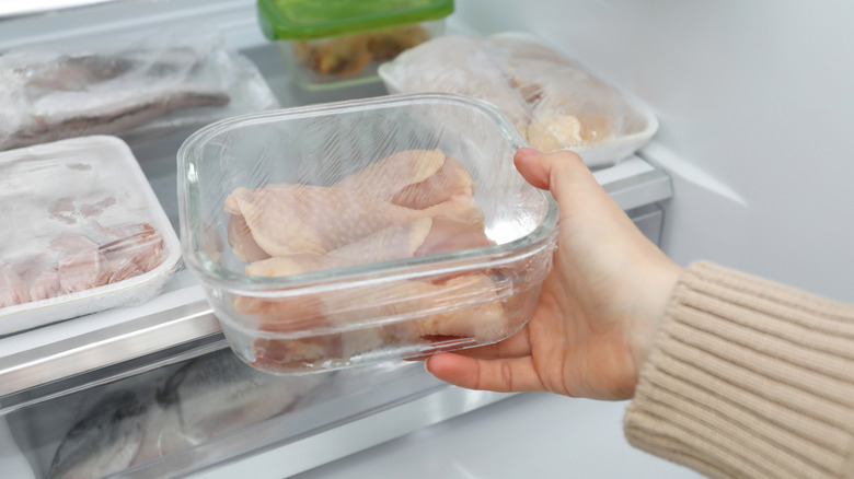 woman thawing frozen chicken in the fridge