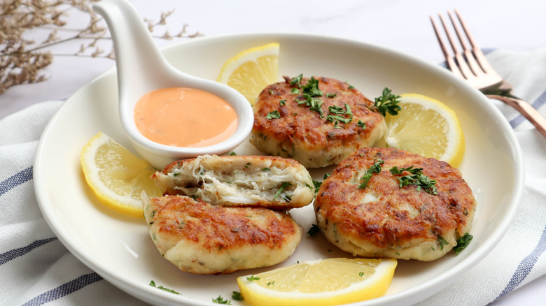 Crab cakes with remoulade on a plate with lemon wedges