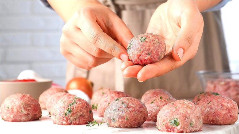 Hands forming raw meatballs