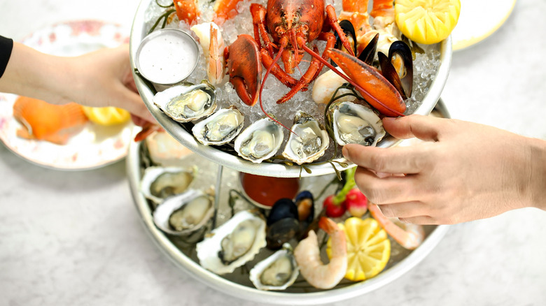 A seafood tower with hands grabbing items