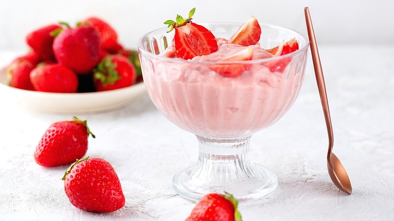 Strawberry mousse in a clear raised bowl topped with fresh strawberries