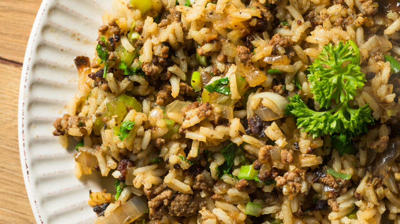 A plate of dirty rice with loads of seasoning, meat, and garnish