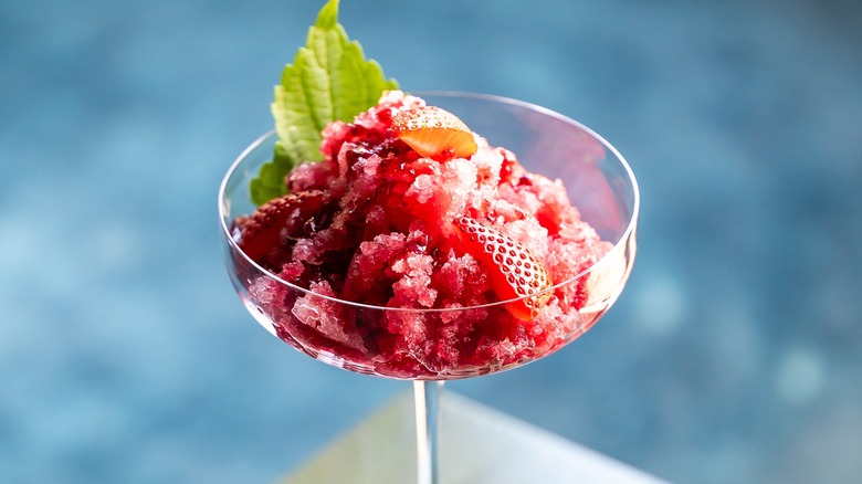 Red granita with strawberries in a tall glass