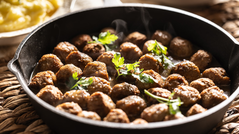 meatballs lined up inside a cast iron baking dish