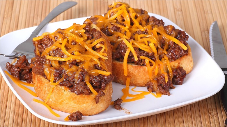 Sloppy Joes with shredded cheddar cheese on garlic toast