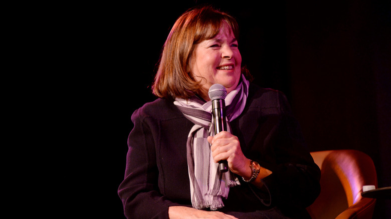 Celebrity chef Ina Garten sits on stage at an event with a mic in hand
