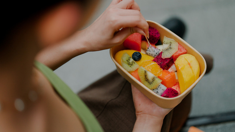 a closeup view of someone holding a box of various fruits