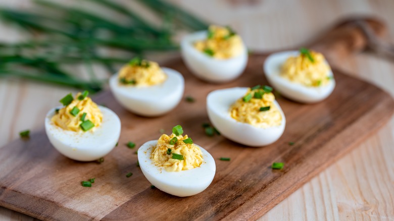 six deviled eggs on a wooden cutting board