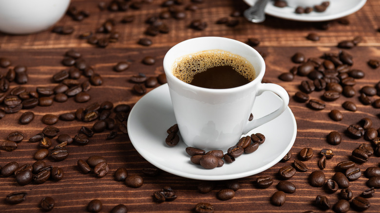 cup of coffee surrounded by beans