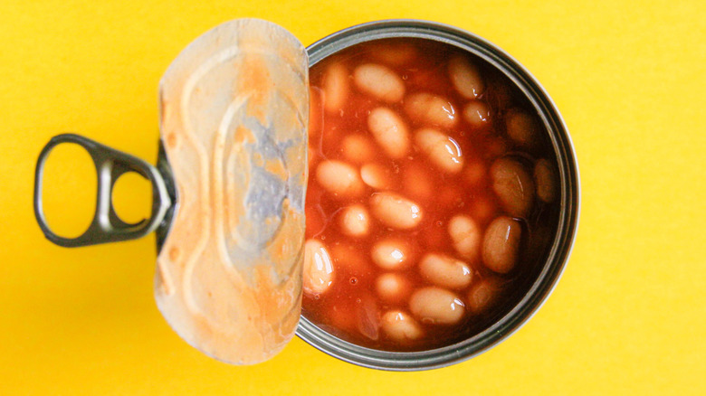An open can of baked beans on a yellow surface