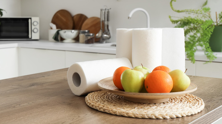 rolls of paper towels on a counter with fruit