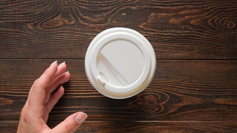 Person reaching for to-go coffee cup