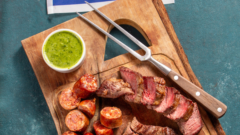 Grilled meat on board with chimichurri sauce