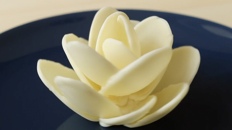 Close-up of a white chocolate flower on a dark blue plate