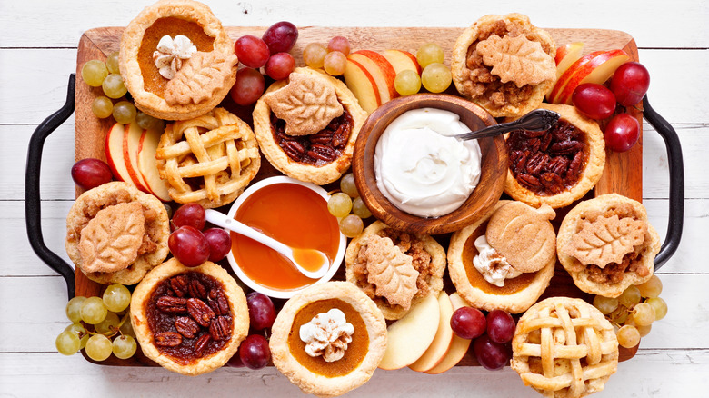 Many mini pie varieties closely arranged on a wooden tray.