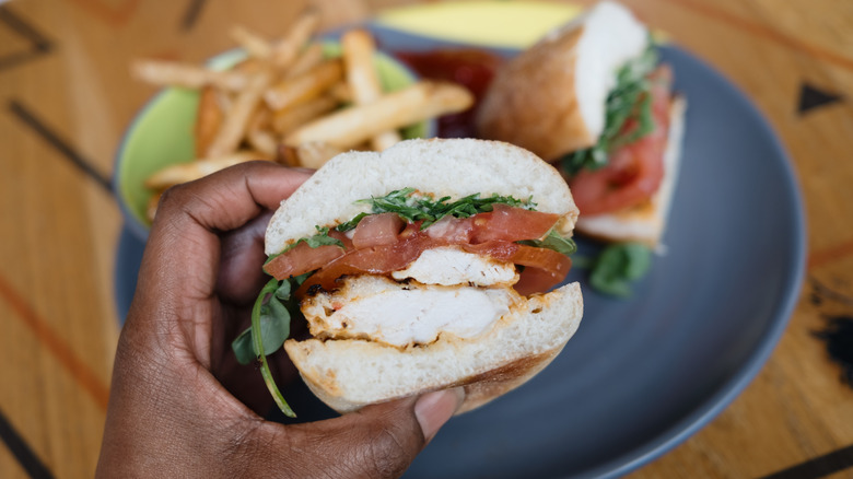 sandwich held in hand over a plate