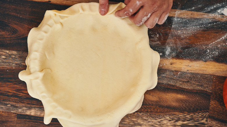 A pie plate with a layer of pie crust inside.