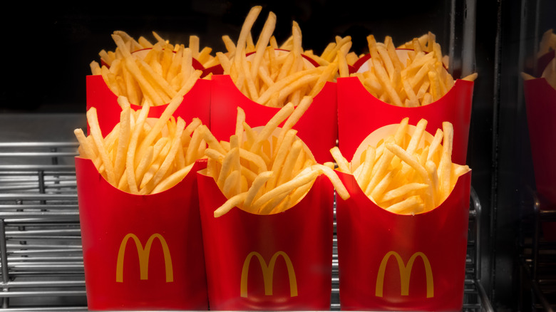 rows of McDonald's fries in logoed fry cups on a cooling rack