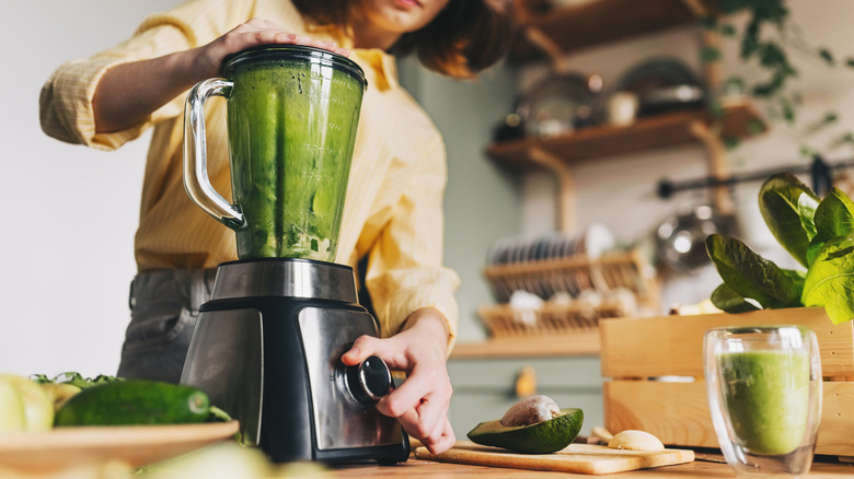Person using a blender to make a green drink
