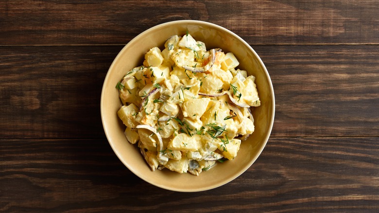Bowl of creamy potato salad on a wooden table.