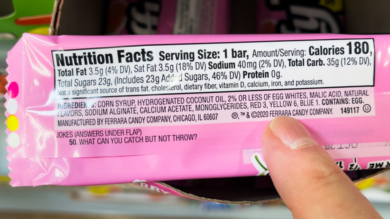 Candy wrapper ingredients list with finger pointing to food dye