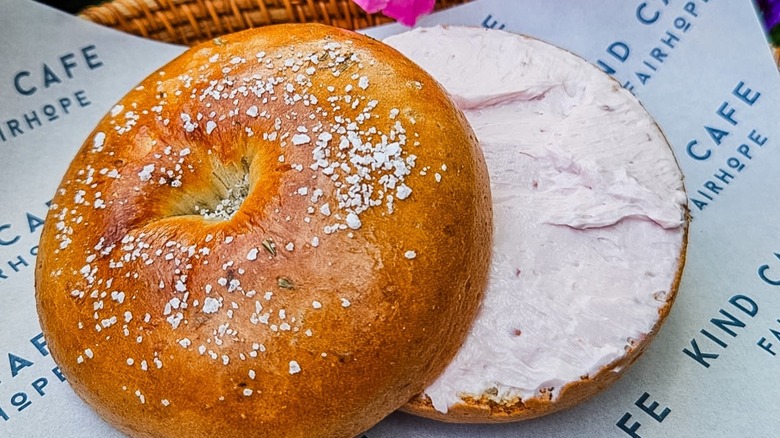 Bagel cut in half with pink cream cheese on Kind Cafe branded paper