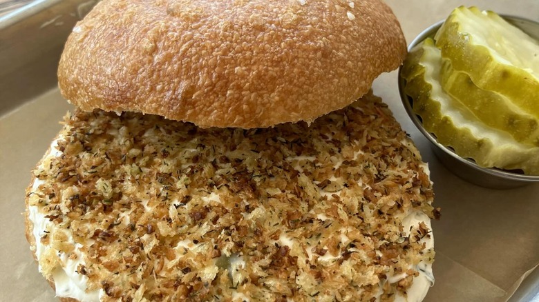 Bagel with cream cheese topped with dill pickled bread crumbs and side of pickle slices