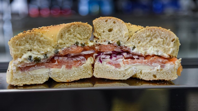 Two halves of a bagel with lox, cream cheese, and onion.