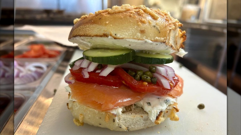 Bagel sandwich with lox, capers, onions, peppers, and sliced cucumber