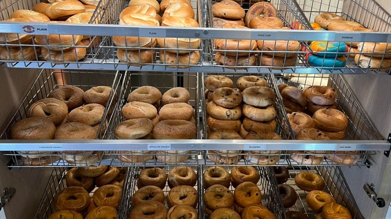 Assortment of bagels in various wire bins on shelves