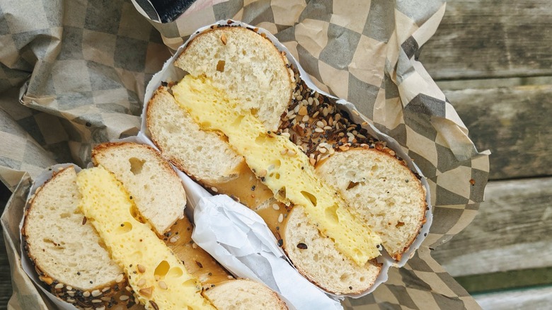 Everything bagel sandwich cut in half to reveal eggs