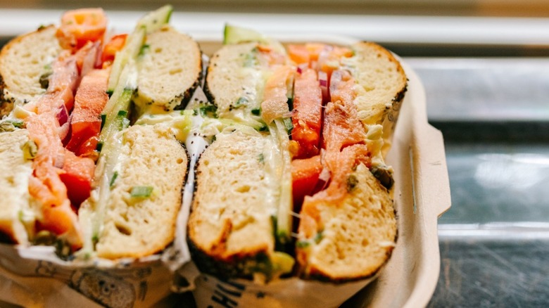 Two halves of a bagel sandwich wrapped and in a container