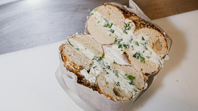Two halves of a cream cheese bagel wrapped in paper