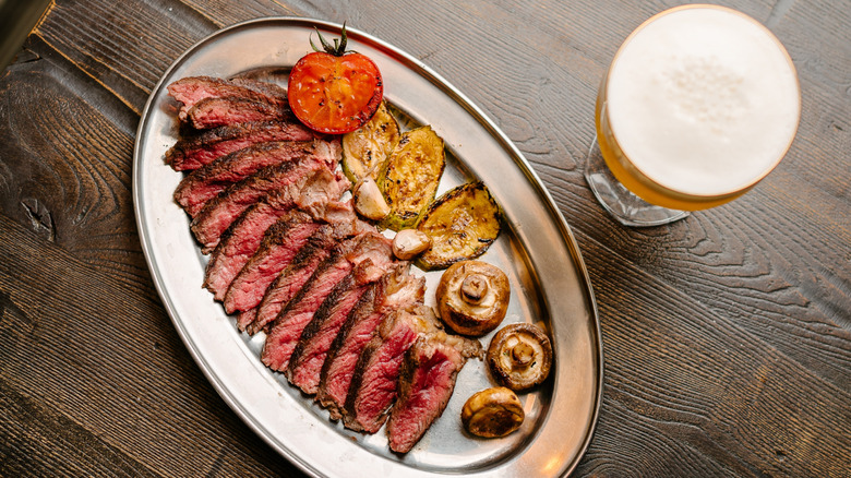 Sliced boneless ribeye with vegetables and a glass of beer