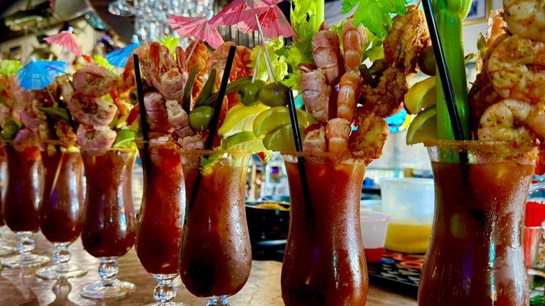 A row of Captain Al's Bloody Marys with shrimp skewers
