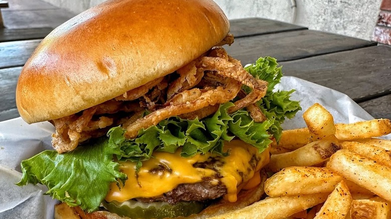 A cheeseburger with frizzled onions and fries from Bar Code Burgers.