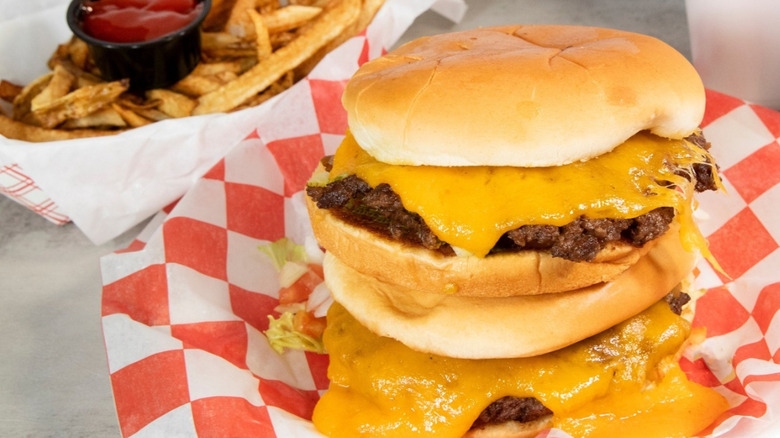 A stack of cheeseburgers and a basket of fries at Chris Madrids.