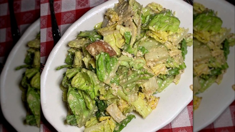 A Caesar salad on a white oval plate