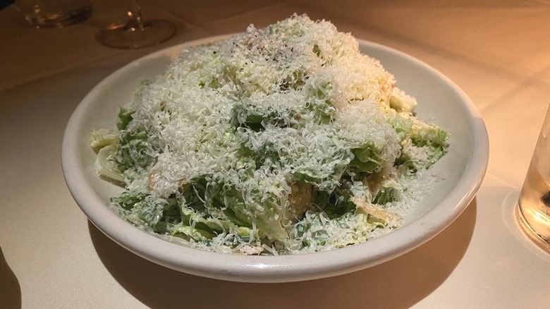 A Smoked Whitefish Caesar salad topped with a generous amount of shredded Parmesan cheese in a white bowl