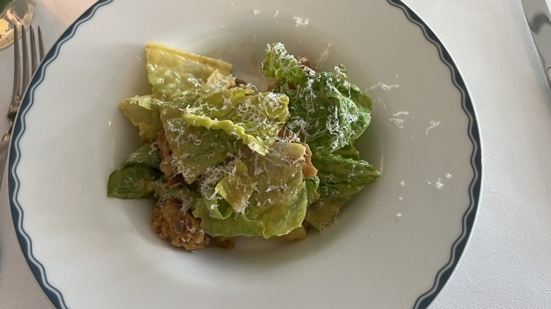 A Caesar salad in a white bowl on a white tablecloth