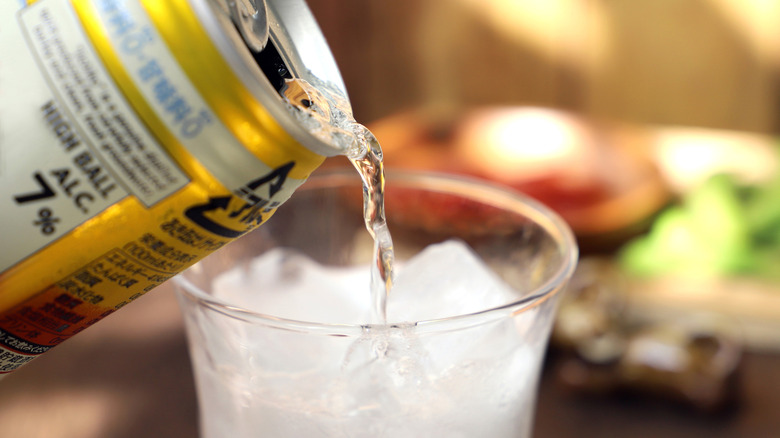Canned cocktail pouring into a glass of ice