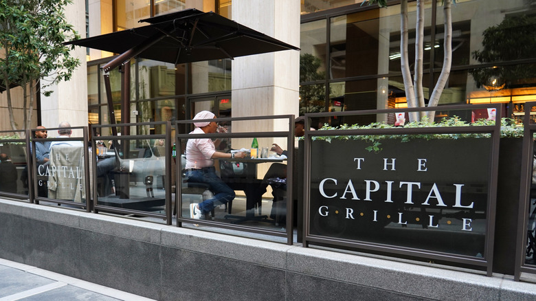 Patio seating at The Capital Grille, where a few diners are enjoying their food
