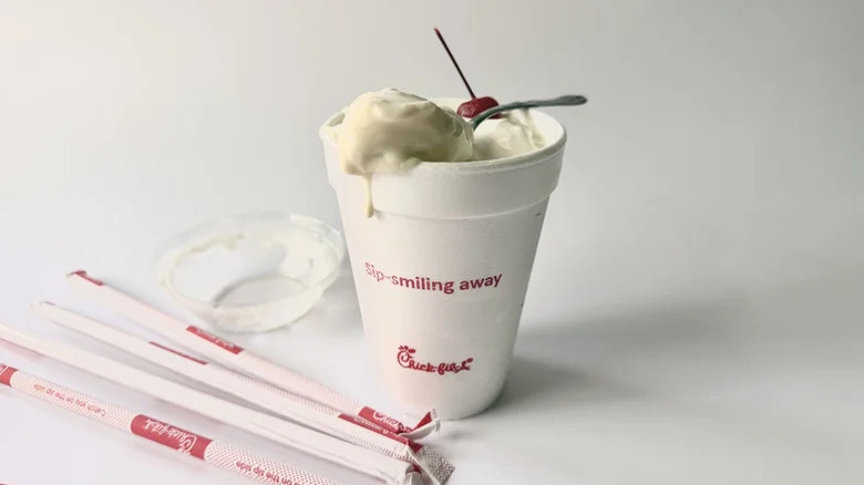 Chick-fil-A's vanilla milkshake served with a cherry on top next to four straws