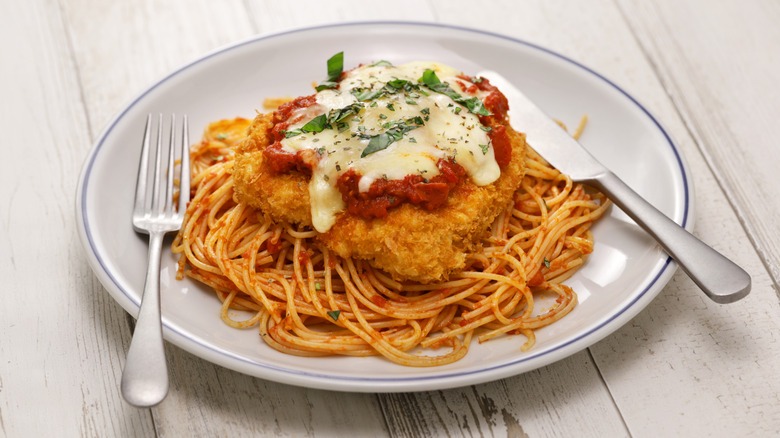A plate of chicken parm with a knife and fork